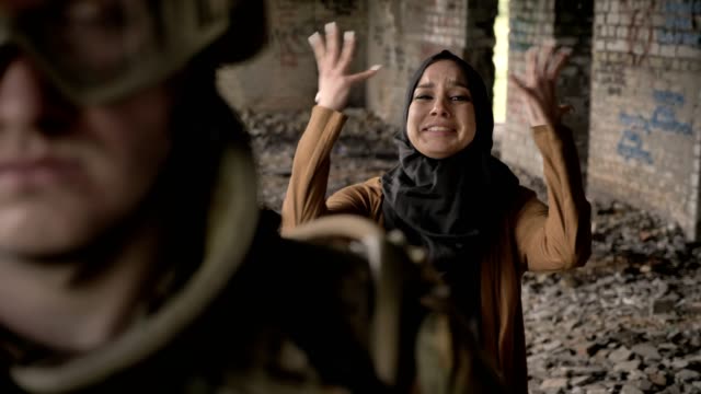 Joven-musulmana-hijab-gritando-y-llorando-detrás-de-soldado-armado,-en-abandonado-edificio,-concepto-de-guerra