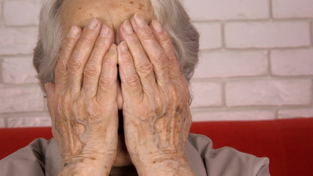 Woe.-An-elderly-woman-covers-face-with-hands