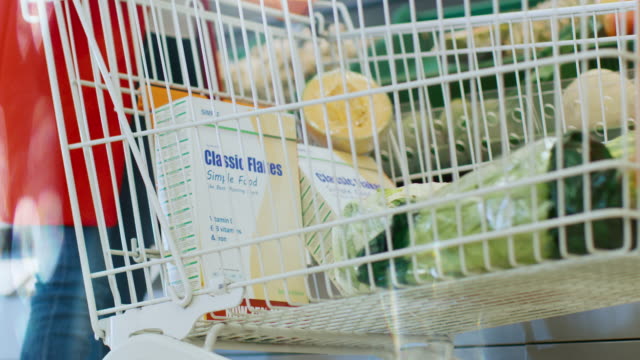 En-el-supermercado:-ángulo-bajo-tiro-de-la-piña-orgánica-de-tomar-mujer-de-la-sección-de-producto-fresco-y-lugares-en-la-cesta-de-la-compra.