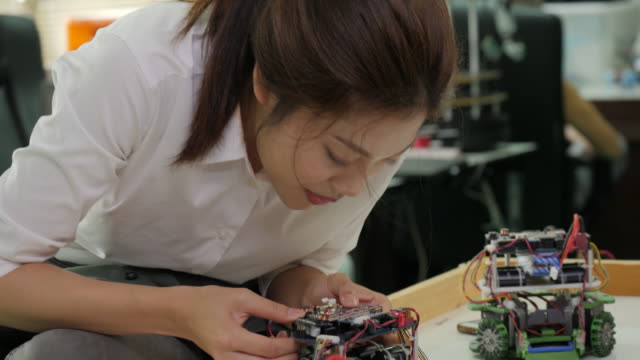 Weibliche-Elektroniker-arbeitet-mit-Roboter,-Aufbau,-Befestigung-Robotik-in-Werkstatt.-Menschen-mit-Technologie-oder-Innovation-Konzept.