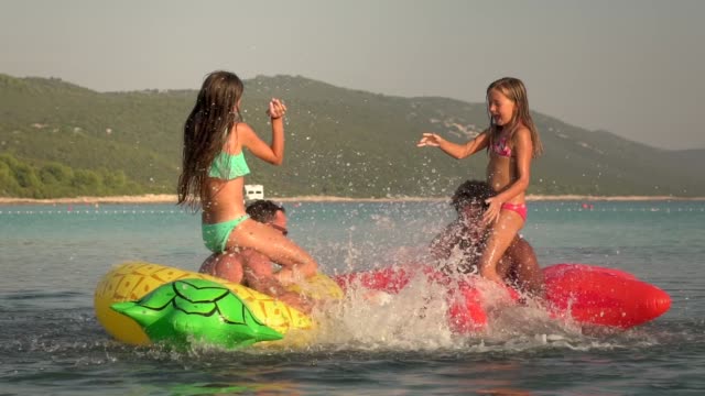 Slow-motion-view-of-fathers-and-daughters-having-a-play-fight-in-sea.