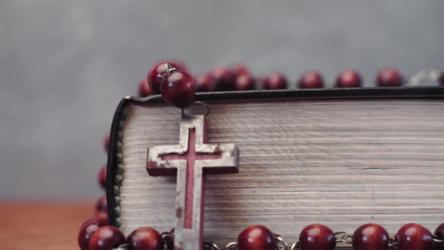 Biblia-y-el-crucifijo-granos-sobre-una-mesa-de-madera-rojo-Fondo-hermoso.-Concepto-de-la-religión-de-cerca