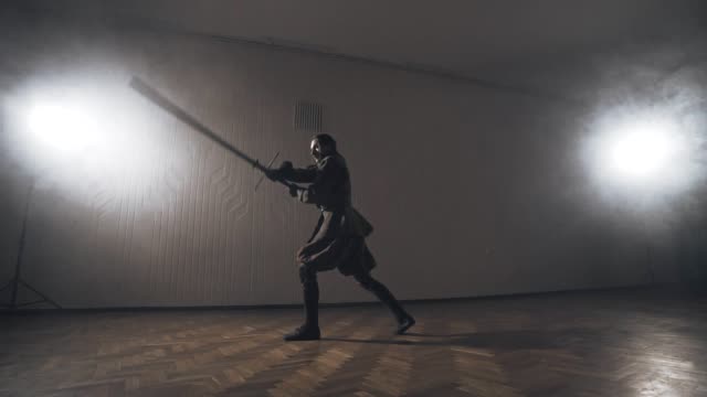 Medieval-warrior-training-with-two-handed-sword-indoors-in-slow-motion