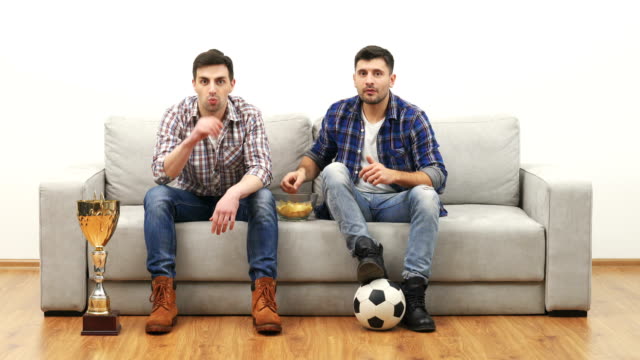 Die-beiden-Männer-schauen-Fußball-auf-dem-Sofa-und-Essen-chips