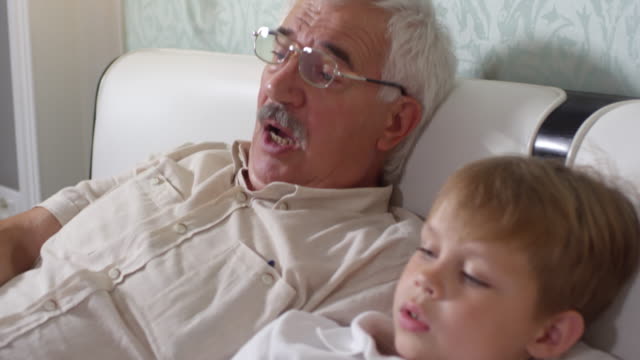 Senior-woman-am-Bett-liegen-und-Fernsehen-mit-Enkel