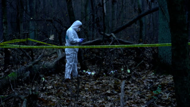 Männliche-forensischen-Experten-in-Schutzausrüstung-arbeiten-bei-Mordstätte-im-Wald