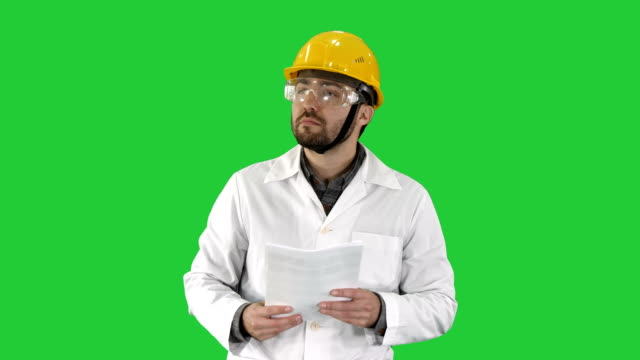Site-engineer-cheching-papers-and-something-around-him-on-a-Green-Screen,-Chroma-Key