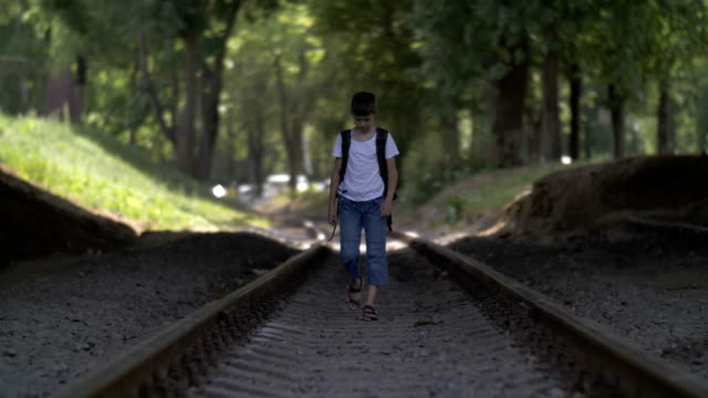 offended-boy-in-depression-walks-along-the-railway-track,-bowing-head,-regrets-for-action,-deep-reflection,-not-successful-first-love-concept,-outdoors