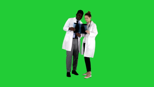 Young-female-doctor-and-afro-american-doctor-looking-at-the-x-ray-picture-of-lungs-on-a-Green-Screen,-Chroma-Key