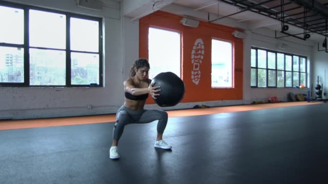 Fit-athletic-young-woman-brunette-training-with-medicine-ball-at-gym-healthy-body-workout-for-kickboxing.-Slow-Motion.