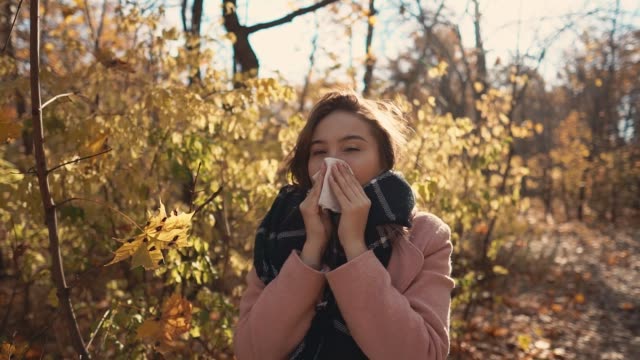 Junge-kranke-Frau-steht-Niesen-im-Park-in-Herbsttag,-mit-Taschentuch