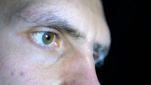 Close-up-of-the-eyes-and-face-of-a-young-man-working-at-a-computer-on-a-Black-Background