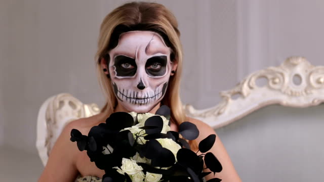 Mädchen-in-einem-Kleid-mit-einem-Blumenstrauß-und-Make-up-in-Form-eines-Skeletts