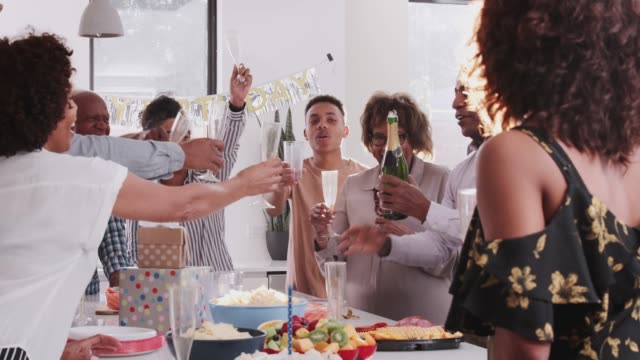 Mittlere-schwarze-Männer-öffnen-und-servieren-Champagner-bei-einer-Familienfeier,-über-Schulter-Blick