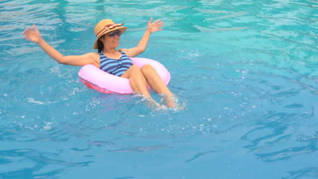 Girl-playing-and-swimming-on-ring-rubber-floating-on-swimming-pool