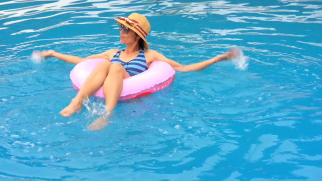 Girl-playing-and-swimming-on-ring-rubber-floating-on-swimming-pool