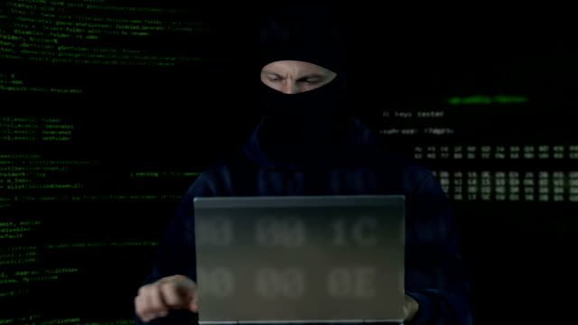 Criminal-in-mask-checking-surveillance-camera-on-laptop-and-phone,-database