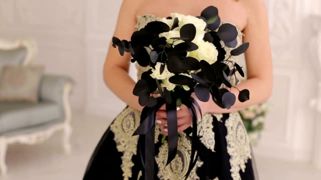 A-young-blonde-in-a-black-dress-with-a-bouquet-of-black-flowers.-Halloween.