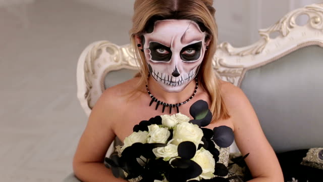 Portrait-of-woman-with-terrifying-halloween-skeleton-makeup-sitting-on-a-sofa.
