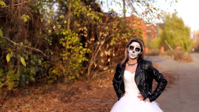 A-young-girl-with-a-creepy-make-up-in-the-form-of-a-skull-on-a-empty-road.