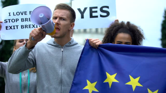 Mann-mit-Megafon-skandiert-Menschenrechtsslogan-schwenkt-Flagge,-Rechtsvorherrschaft-in-der-EU