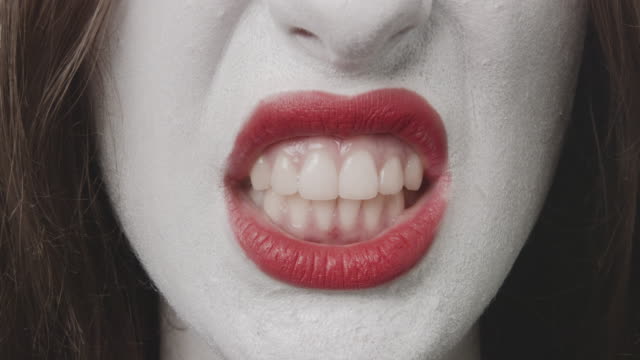 Entblößen-die-Zähne---Nahaufnahme-eines-Teenagers,-der-für-Halloween-oder-eine-Kostümparty-geschminkt-wird.-Proben-verschiedene-Mimik,-entblößt-sie-ihre-Zähne