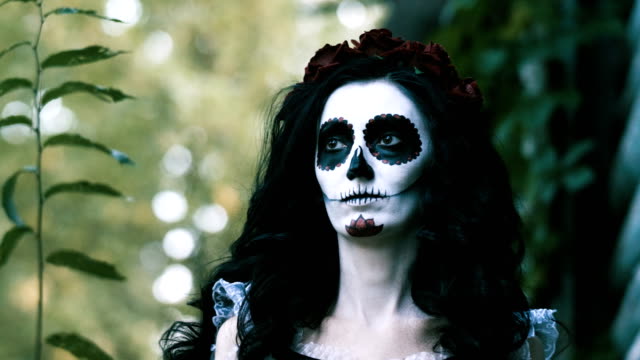 Porträt-der-jungen-Frau-mit-beängstigend-Schädel-Make-up-für-Halloween-in-einem-Wald.-4K