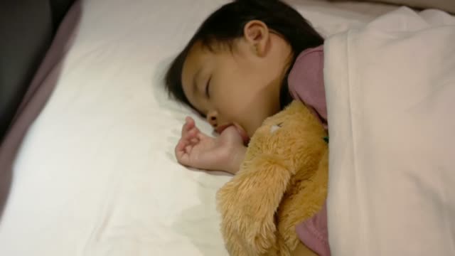 Asiatische-Mutter-legt-Decke-auf-ihre-Tochter,-die-im-Bett-schläft-und-Gute-Nacht-Kuss-mit-Liebe.-Gesundheitskonzept.