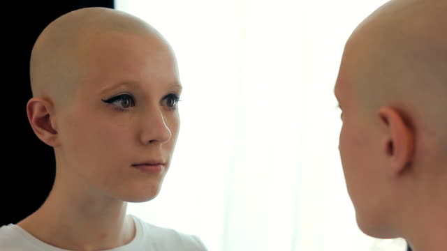 Mujer-triste-que-sufre-de-cáncer-mirando-a-sí-misma-en-el-espejo