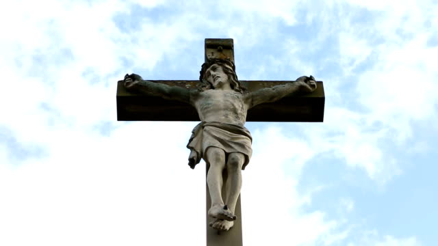 Nahaufnahme-des-steinernen-Kreuz-mit-Jesus-und-blauer-Himmel-mit-Wolken