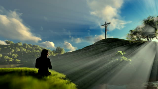 Woman-praying-at-Jesus-cross-over-beautiful-morning-sun-rays