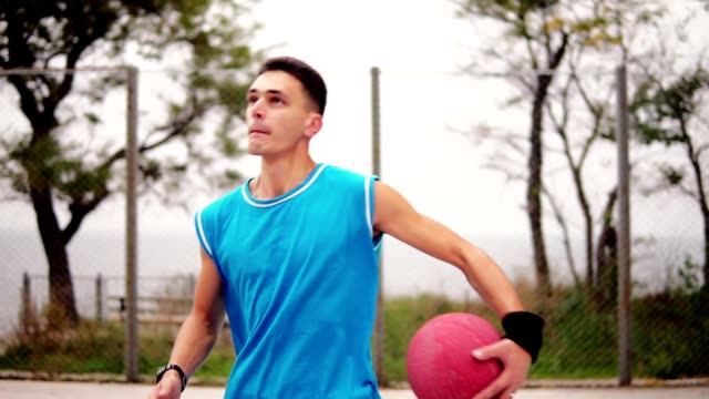 Young-man-running-with-a-ball-and-throwing-a-ball-to-the-basket-successfully.-Basketball-game.-Slowmotion-shot