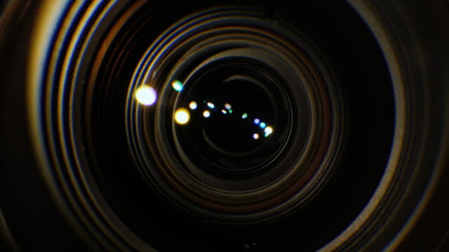 Un-primer-plano-de-la-lente-de-una-cámara-de-vídeo.-La-fuente-de-luz-ilumina-las-lentes,-luego-entra-en-la-oscuridad