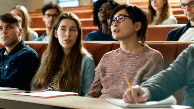 En-el-aula-inteligente-estudiante-asiática-hace-profesor-una-pregunta.-Multi-étnico-grupo-de-estudiantes-brillantes-modernas-en-la-Universidad.