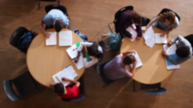 Defocused-Overhead-Shot-Of-High-School-Pupils-In-Group-Study-Around-Table