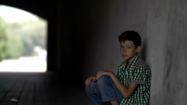 offended-abandoned-boy-sits-in-a-tunnel-on-the-floor,-looks-at-the-camera