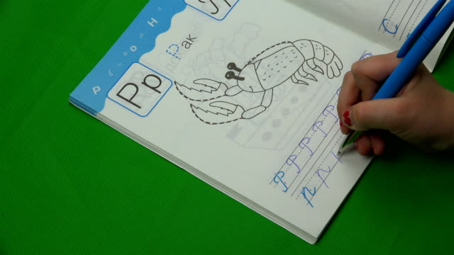 el-niño-escribe-letras-en-un-cuaderno-sobre-un-fondo-verde
