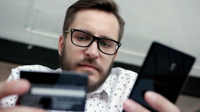 Hombre-usando-Banca-en-línea-con-tarjeta-y-teléfono-inteligente
