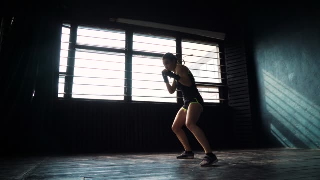 silhouette-beautiful-young-boxing-woman-training-punching-in-fitness-studio