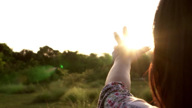 Sunlight-through-female-hands-while-her-looking-at-sun