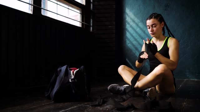 panning-fit-woman-wrapping-hands-with-bandage-tape-preparing-for-boxing-training-slow-motion