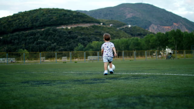 Tracking-camera-of-a-little-boy-scoring-a-goal-in-football-field