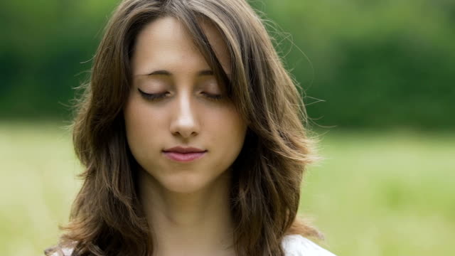 Young-brunette-woman-meditates-outdoors,-close-up-portrait-female-deeply-feels