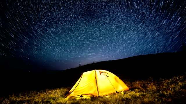 Time-Lapse.-Sterne-Kreisen-über-die-Nacht-Berge-und-eine-glühende-camping-Zelt