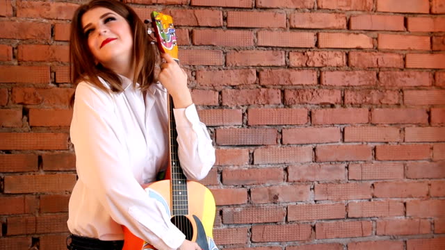 Girl-in-white-shirt-posing-with-a-guitar-in-hippie-style.