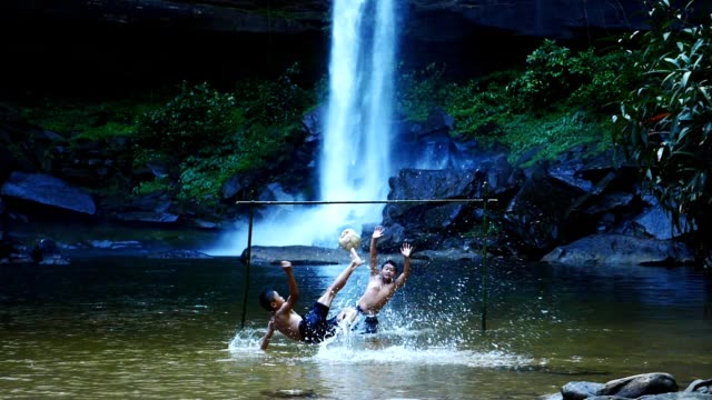 Rural-children-shoots-a-soccer-ball-at-the-waterfall.-(Slow-motion)