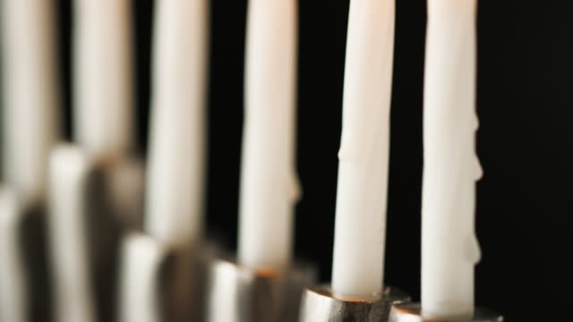Schuss-von-weißen-Kerzen-brennen-in-eine-jüdische-Menora-Leuchter,-selektiven-Fokus-zu-kippen,-Nahaufnahme-detail
