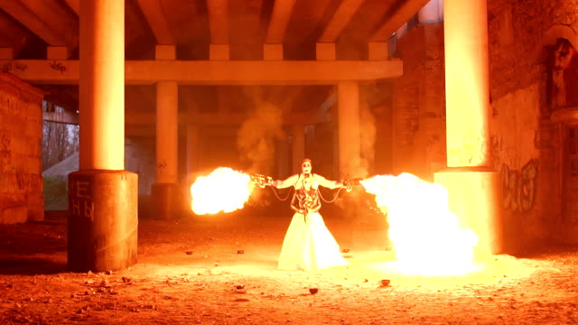 A-couple-in-wedding-dresses-and-with-skull-makeup-perform-a-fire-show.-Halloween