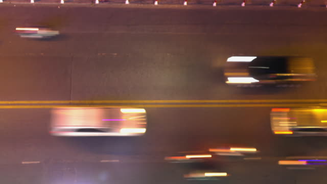 TIMELAPSE:-Blurry-cars-and-motorbikes-drive-up-and-down-the-road-at-night.