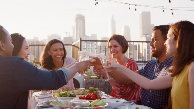 Freunde-versammelt-auf-Dachterrasse-für-Essen-mit-Skyline-der-Stadt-im-Hintergrund